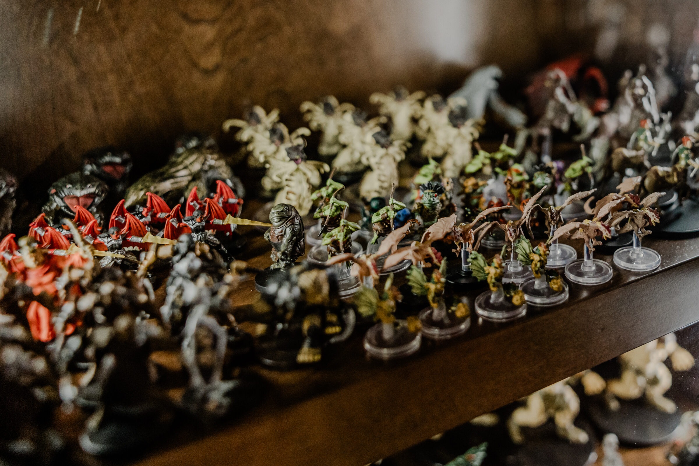 An assortment of detailed miniature fantasy figures, painted with various colors, arranged on shelves, likely for tabletop gaming or collecting.