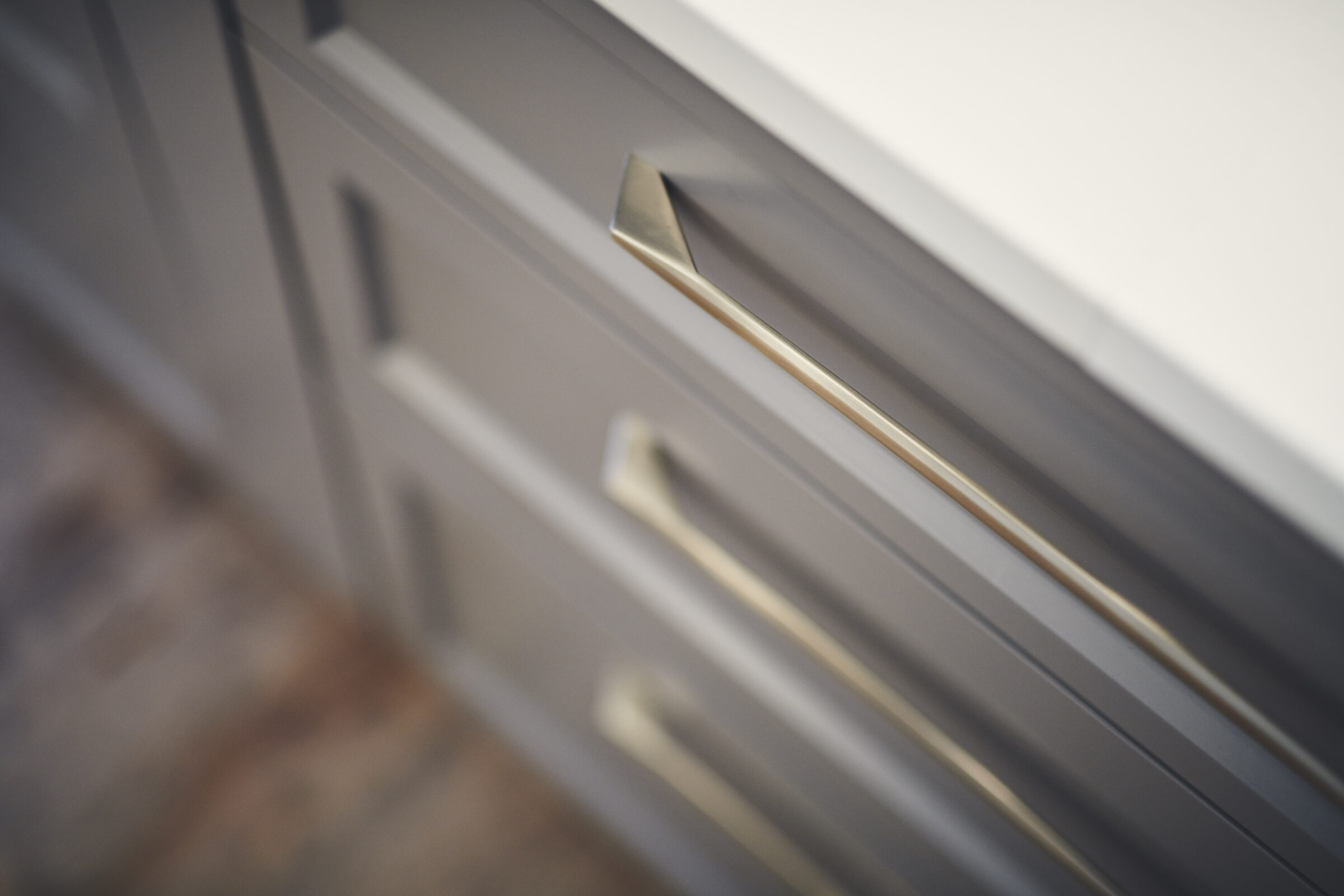 This image shows a close-up of gray drawers with sleek, metallic handles. The focus is shallow with blurred background enhancing the hardware details.