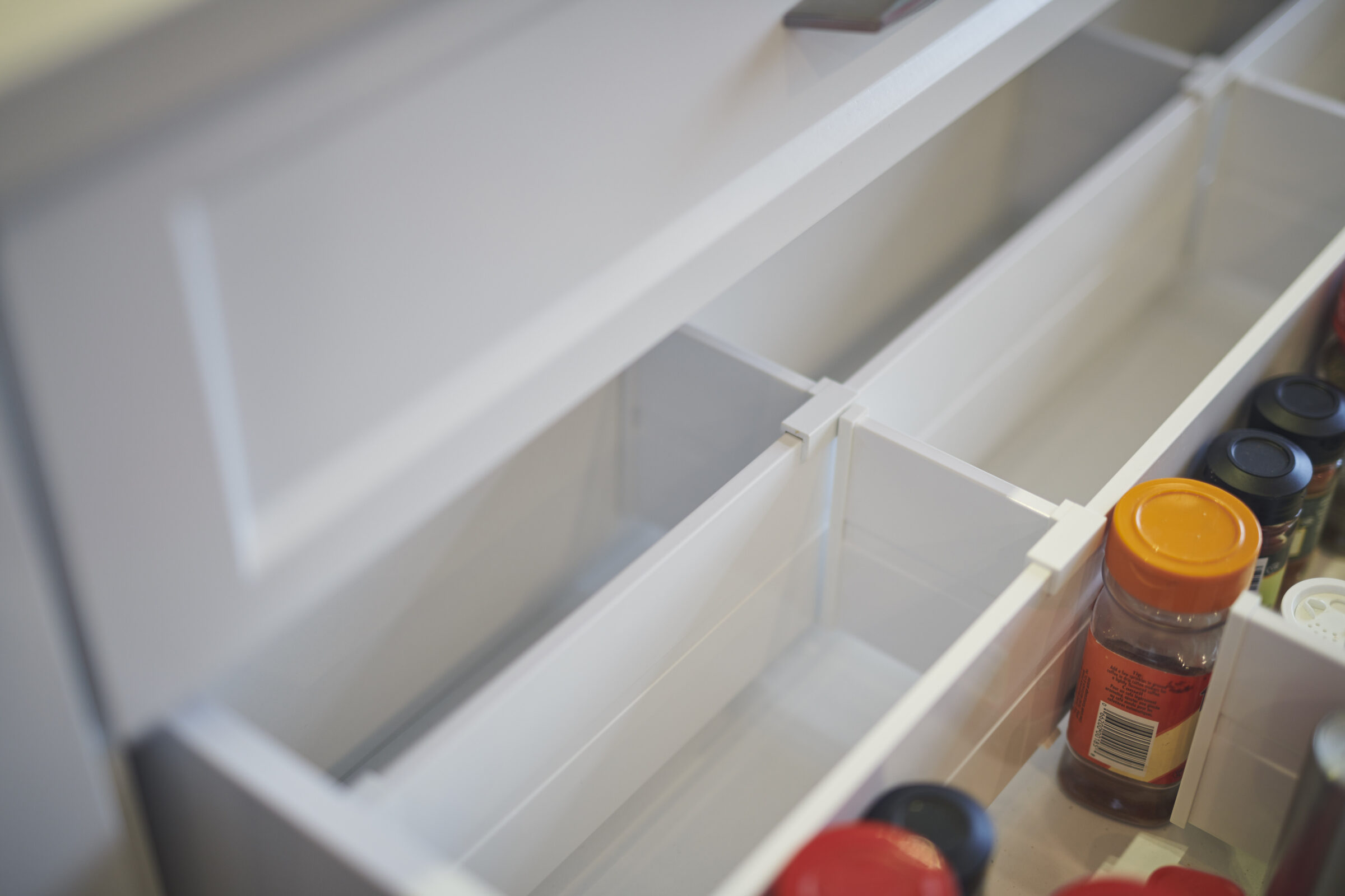 An open refrigerator door with clear, empty shelves, except for a few condiment bottles, including one with an orange cap, visible on the side.