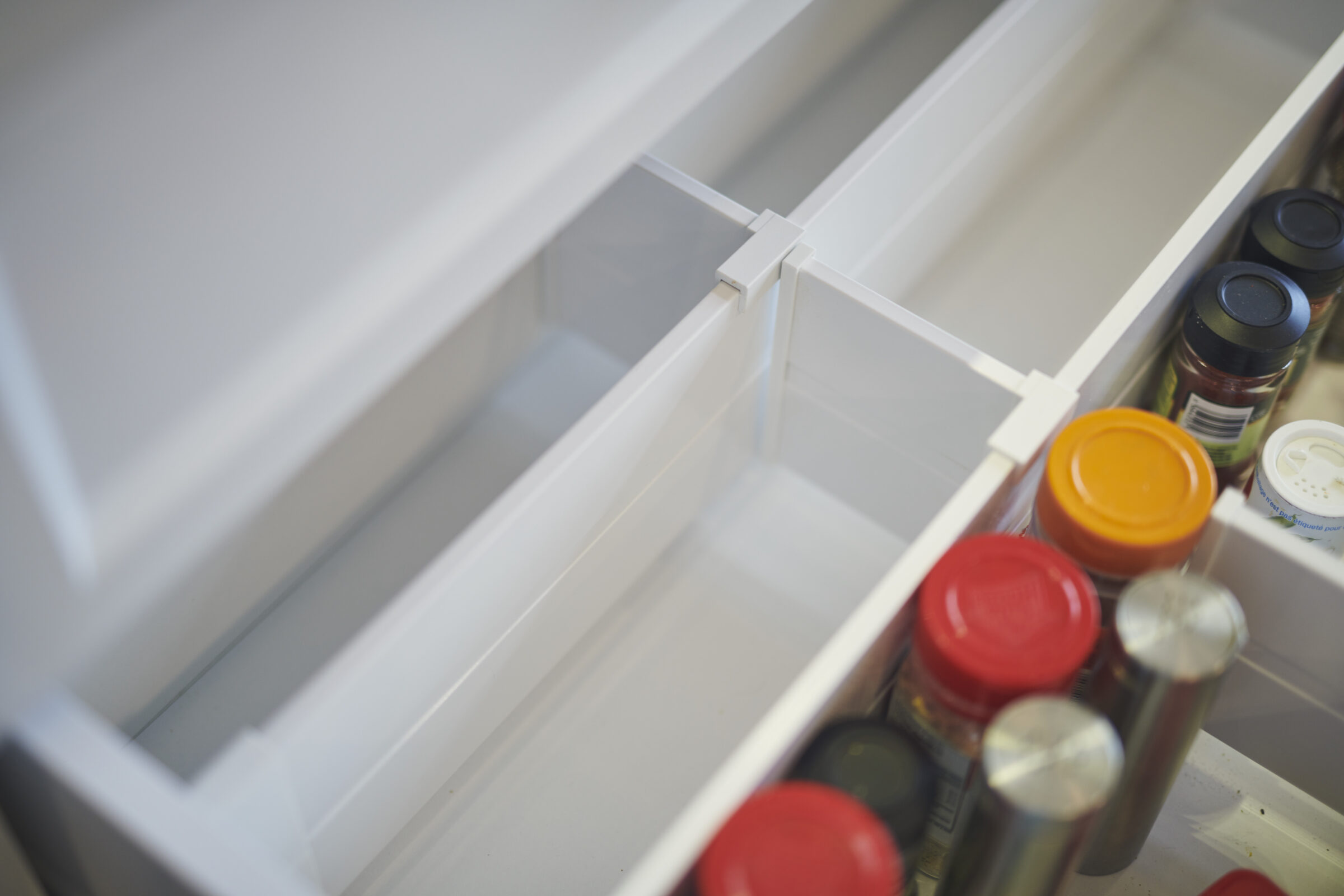 Close-up view inside an open refrigerator door shelf displaying an assortment of condiment jars with various colored lids, slightly out of focus.