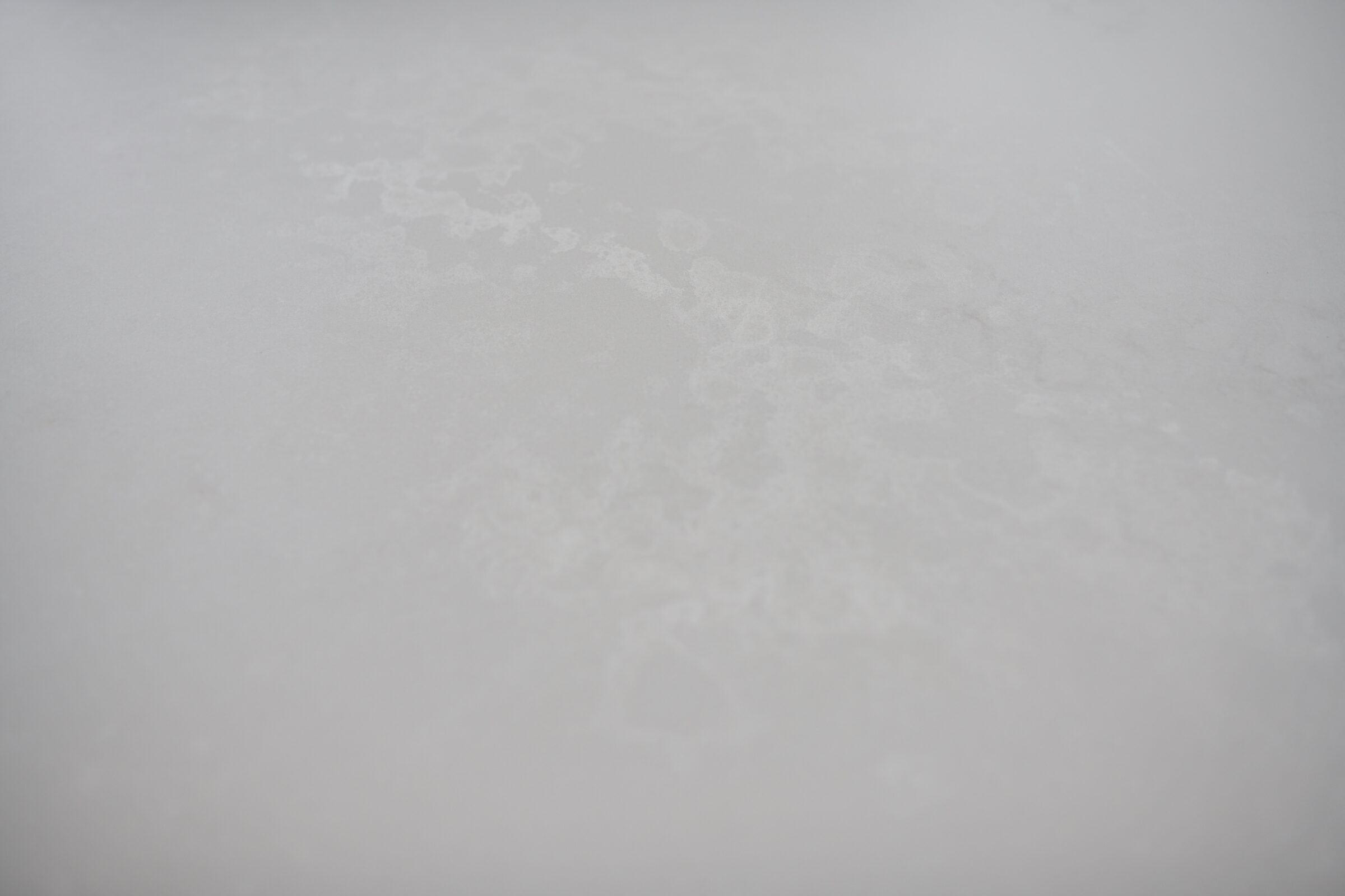 This image shows a close-up view of a textured white surface, resembling compacted snow or frost with subtle variations in shading and patterns.