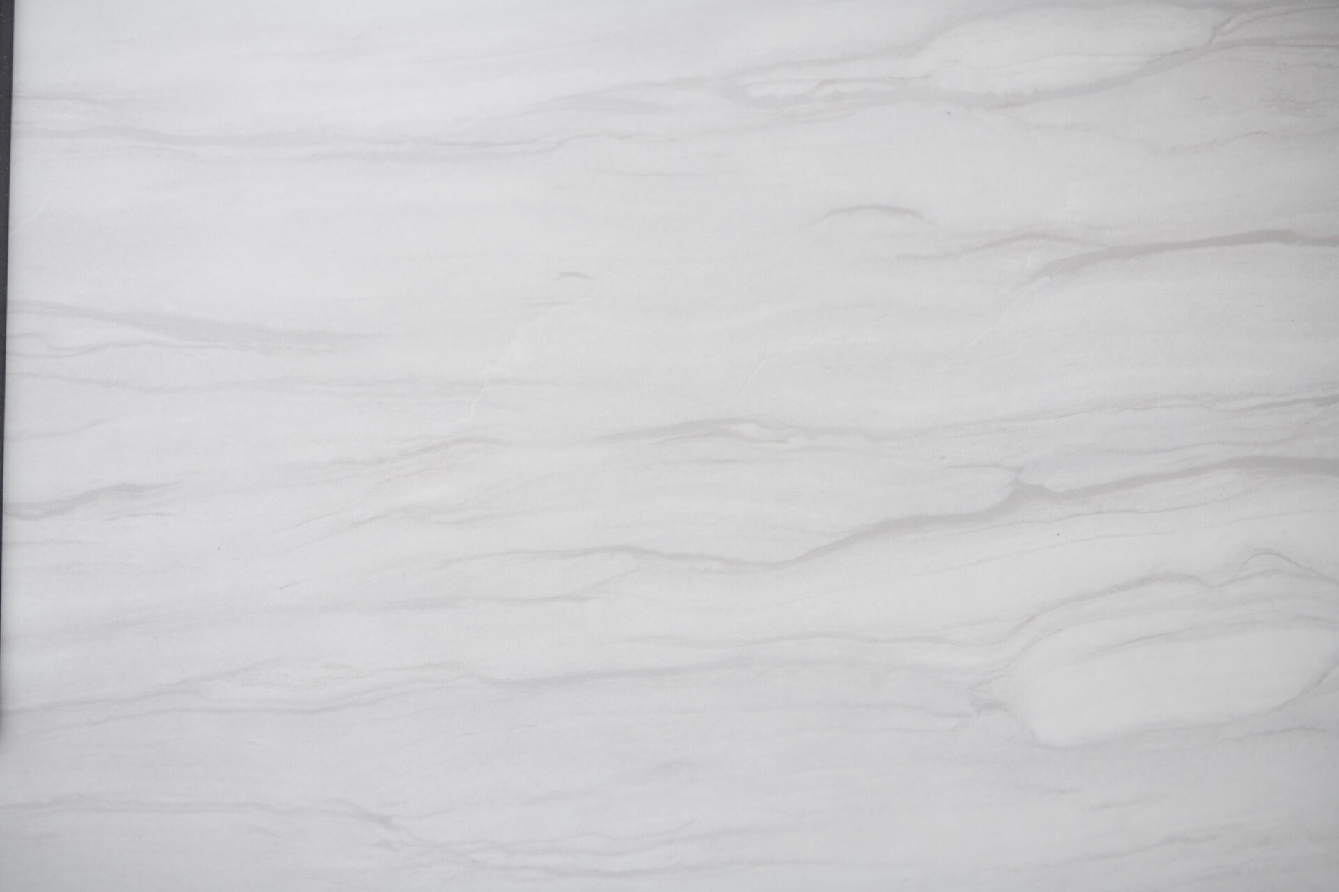 This image displays a smooth white marble surface with subtle gray veins, exhibiting a natural pattern commonly used for luxurious countertops and flooring.