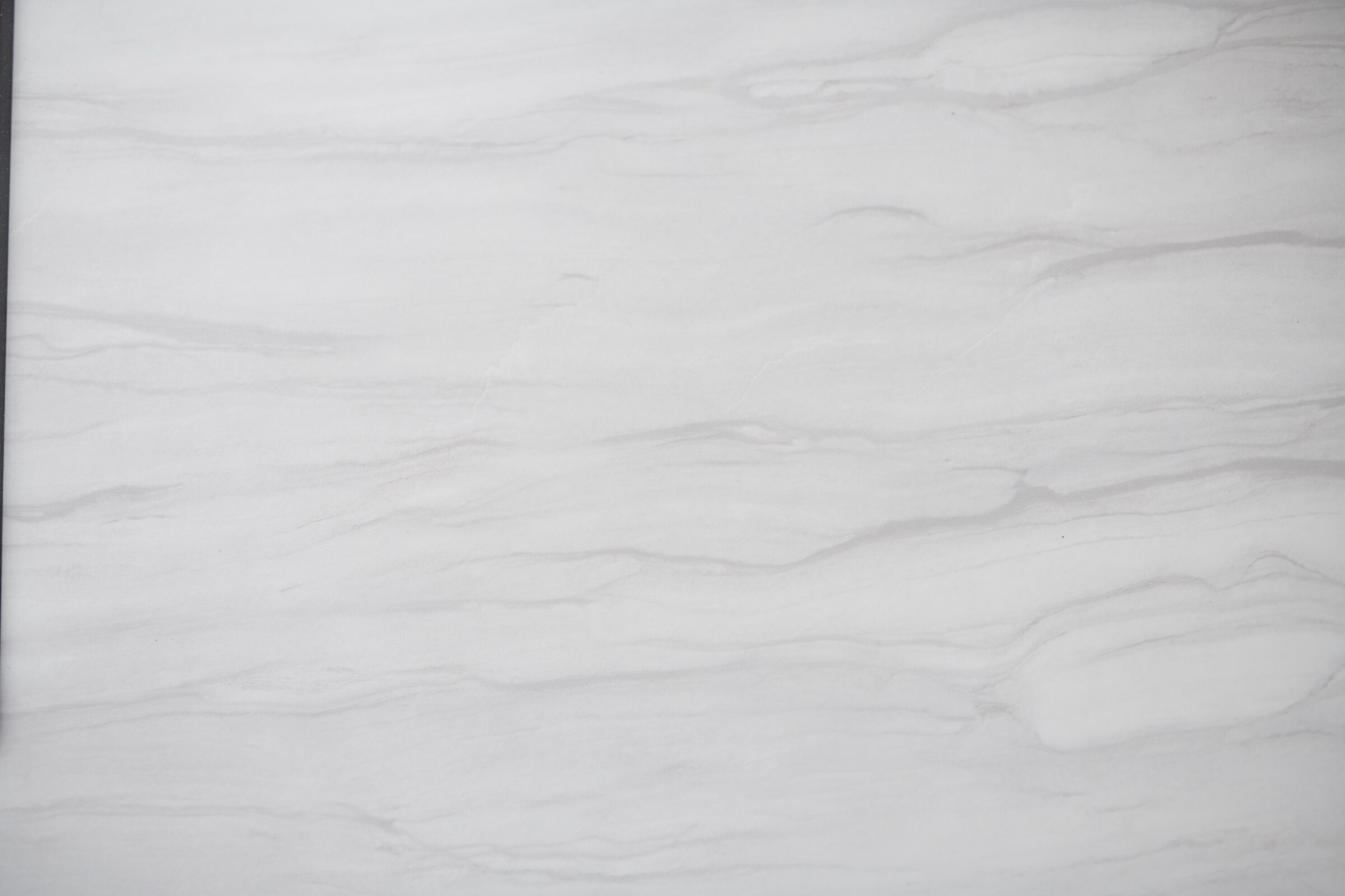 This image displays a smooth white marble surface with subtle gray veins, exhibiting a natural pattern commonly used for luxurious countertops and flooring.
