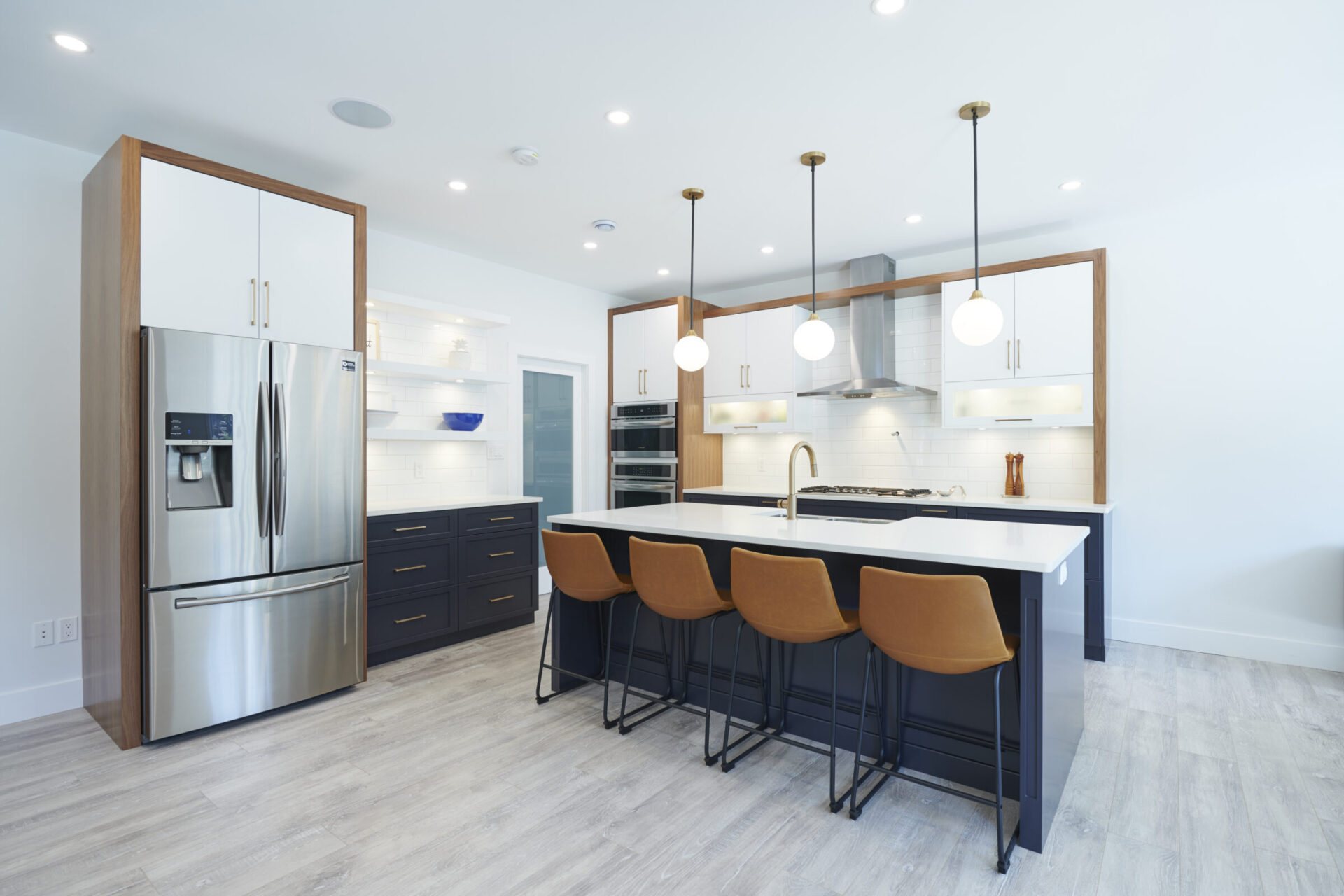 Modern kitchen with stainless steel appliances, white subway tile backsplash, an island with bar stools, and pendant lighting above clean, well-organized counters.