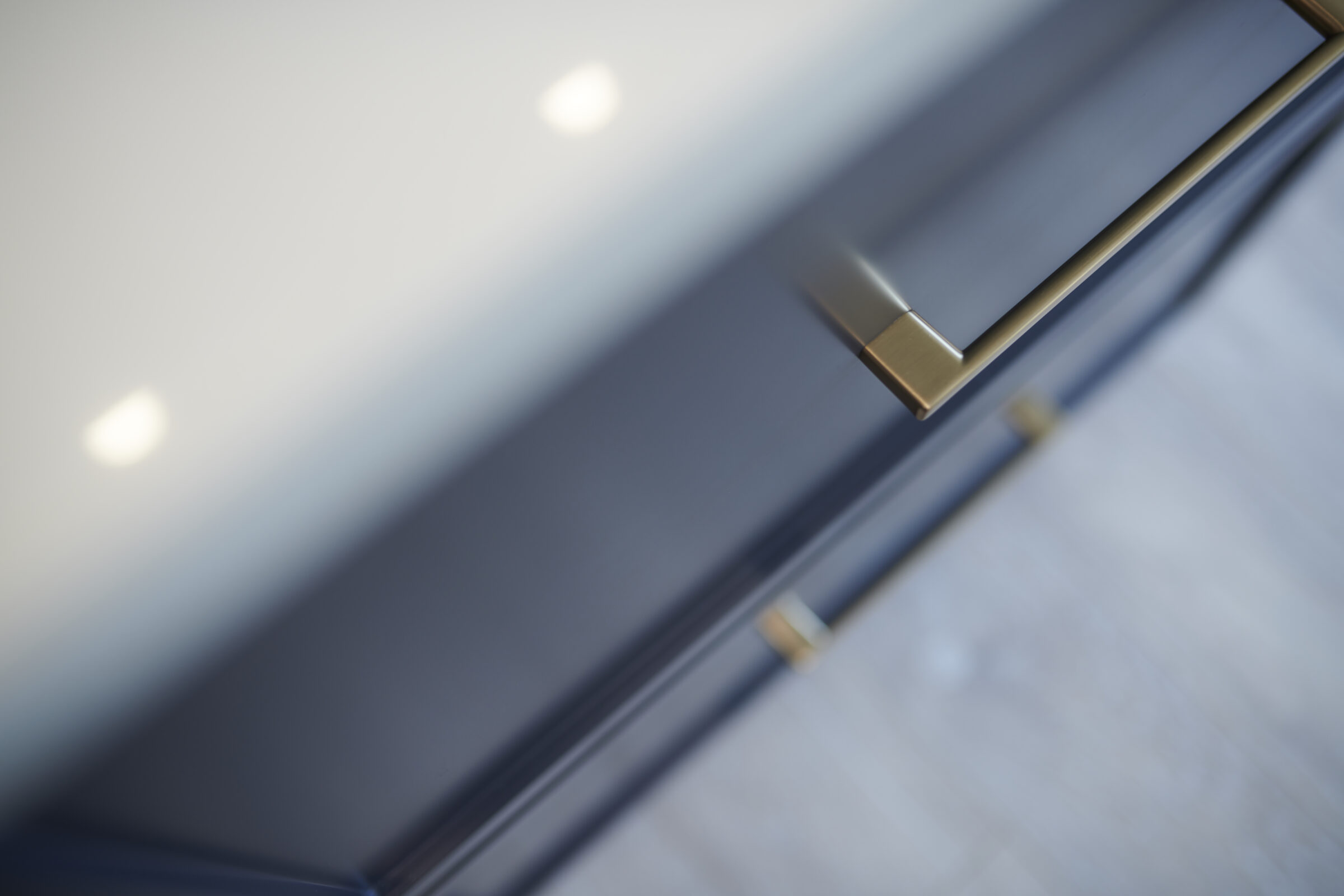 This is a close-up image of a modern kitchen cabinet with brass handles, featuring soft-focus on the background and diffused lighting.