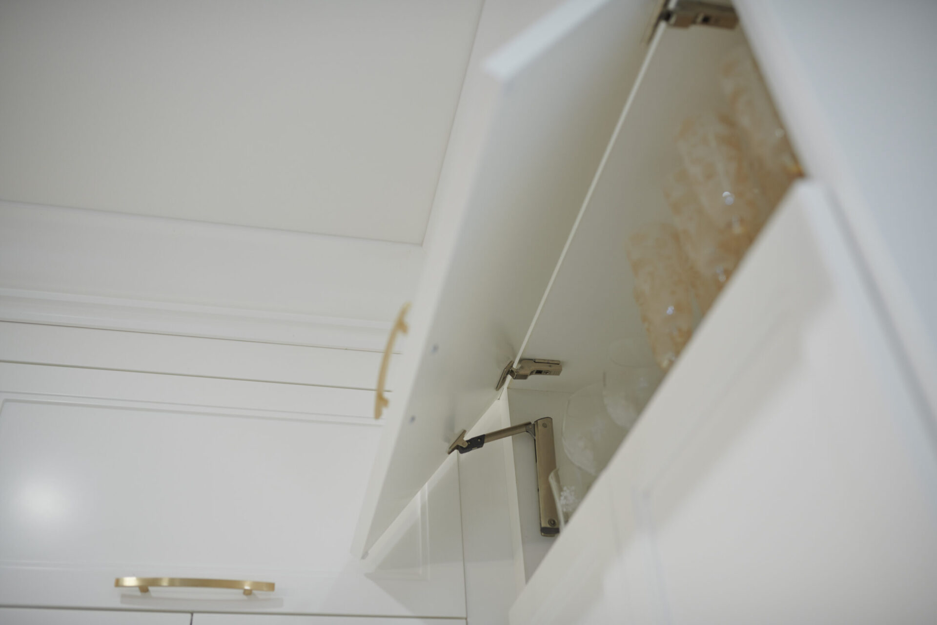 This image shows an open white cabinet with a golden handle. Inside, it appears to be a water spill or leak on the shelf.