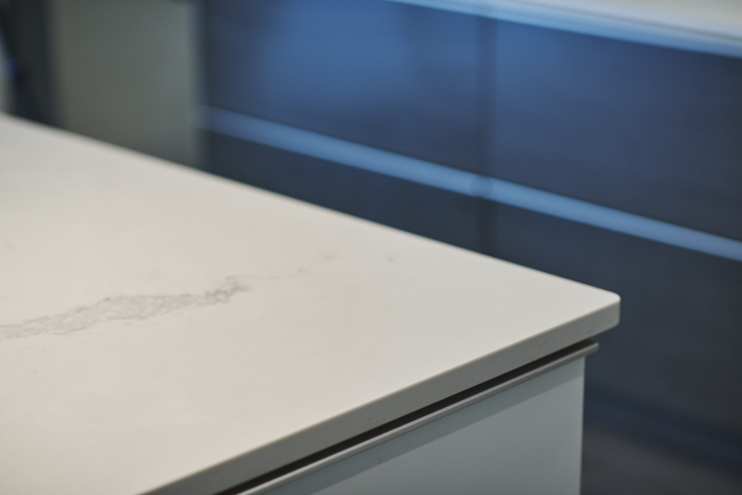 A white tabletop with visible wear marks, set against a blurred blue background, creating a minimalist, modern design with a used feeling.