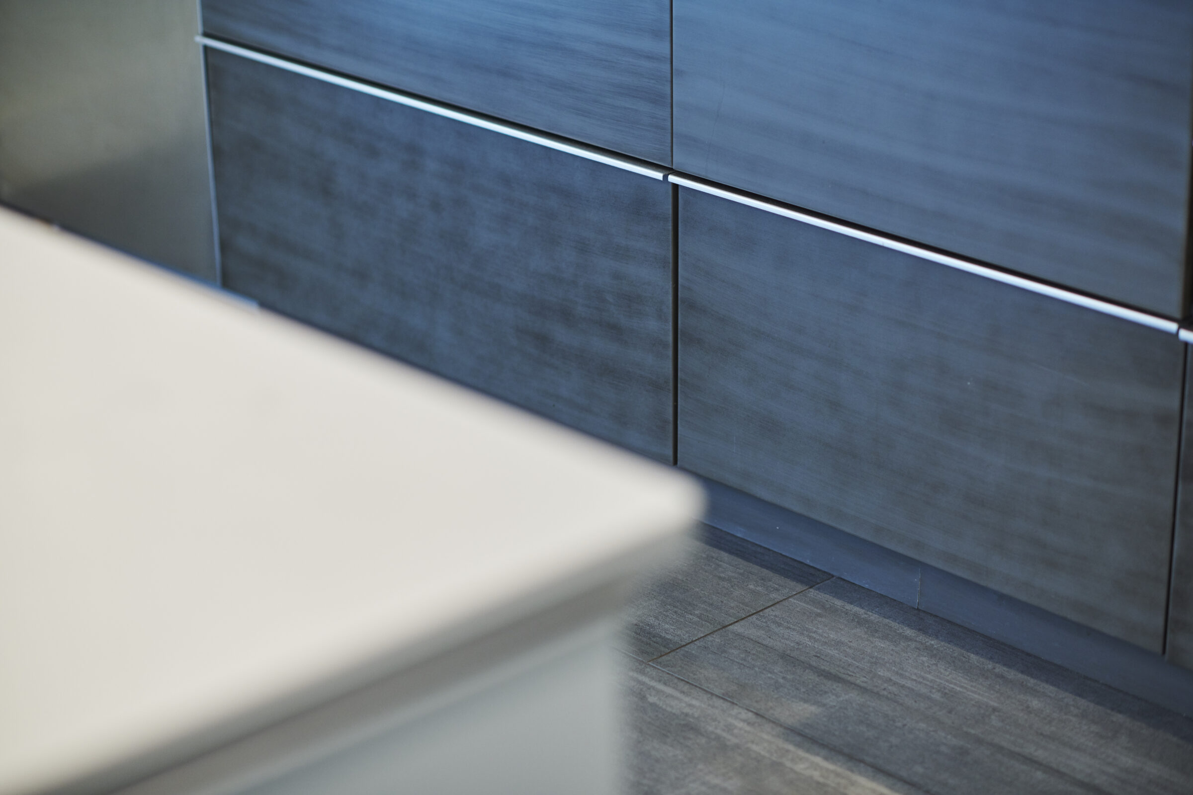 Close-up of a modern kitchen with a focus on sleek gray cabinetry and a blurred countertop in the foreground, depicting clean, minimalist design elements.