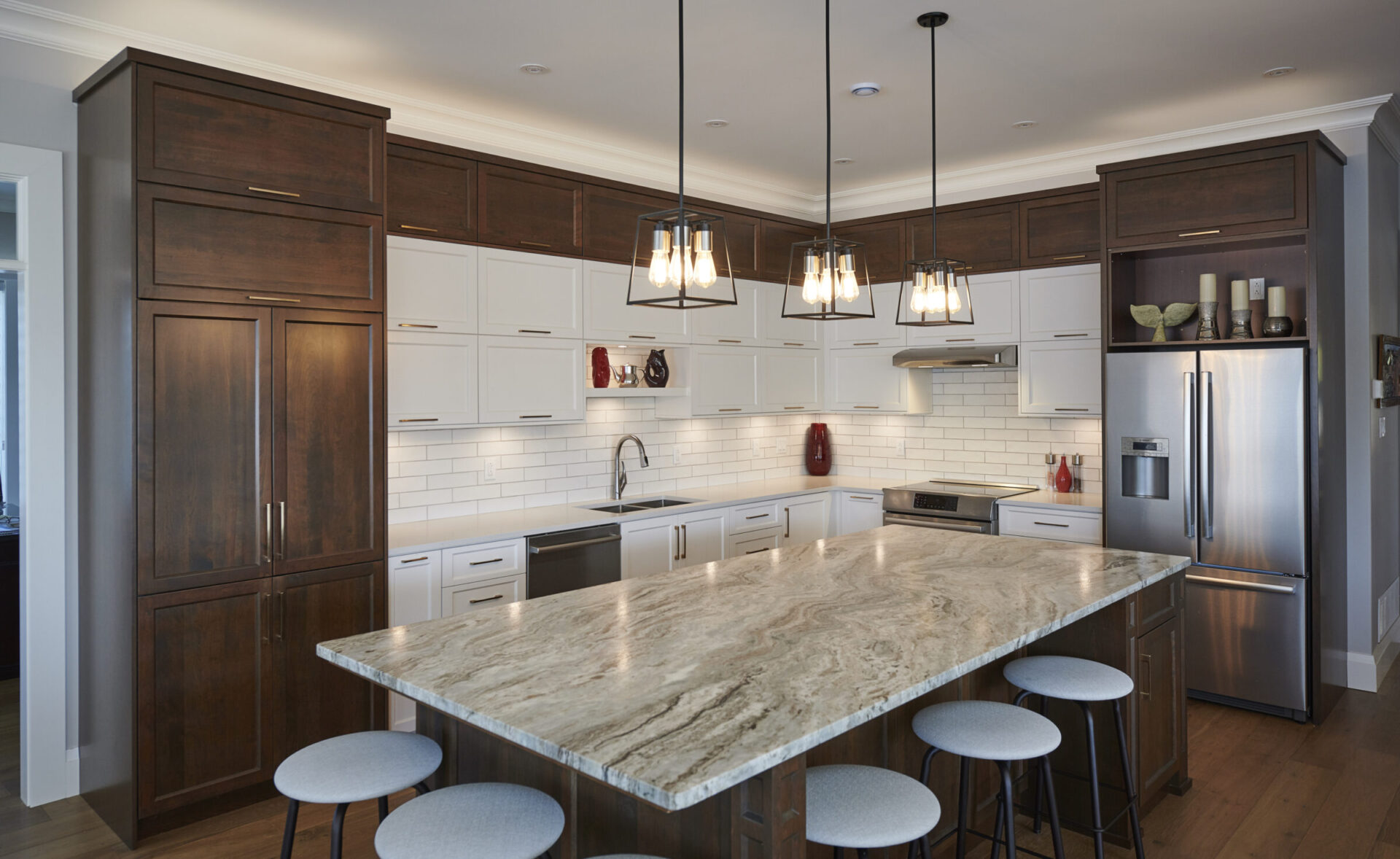 Modern kitchen featuring white cabinetry, dark wood island with marble countertop, stainless steel appliances, subway tiles, and pendant lighting. No people visible.