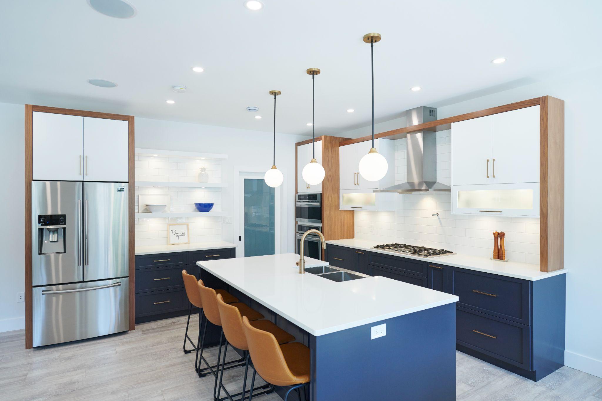 Navy blue kitchen island with leather barstools, gold fixtures, and globe pendants