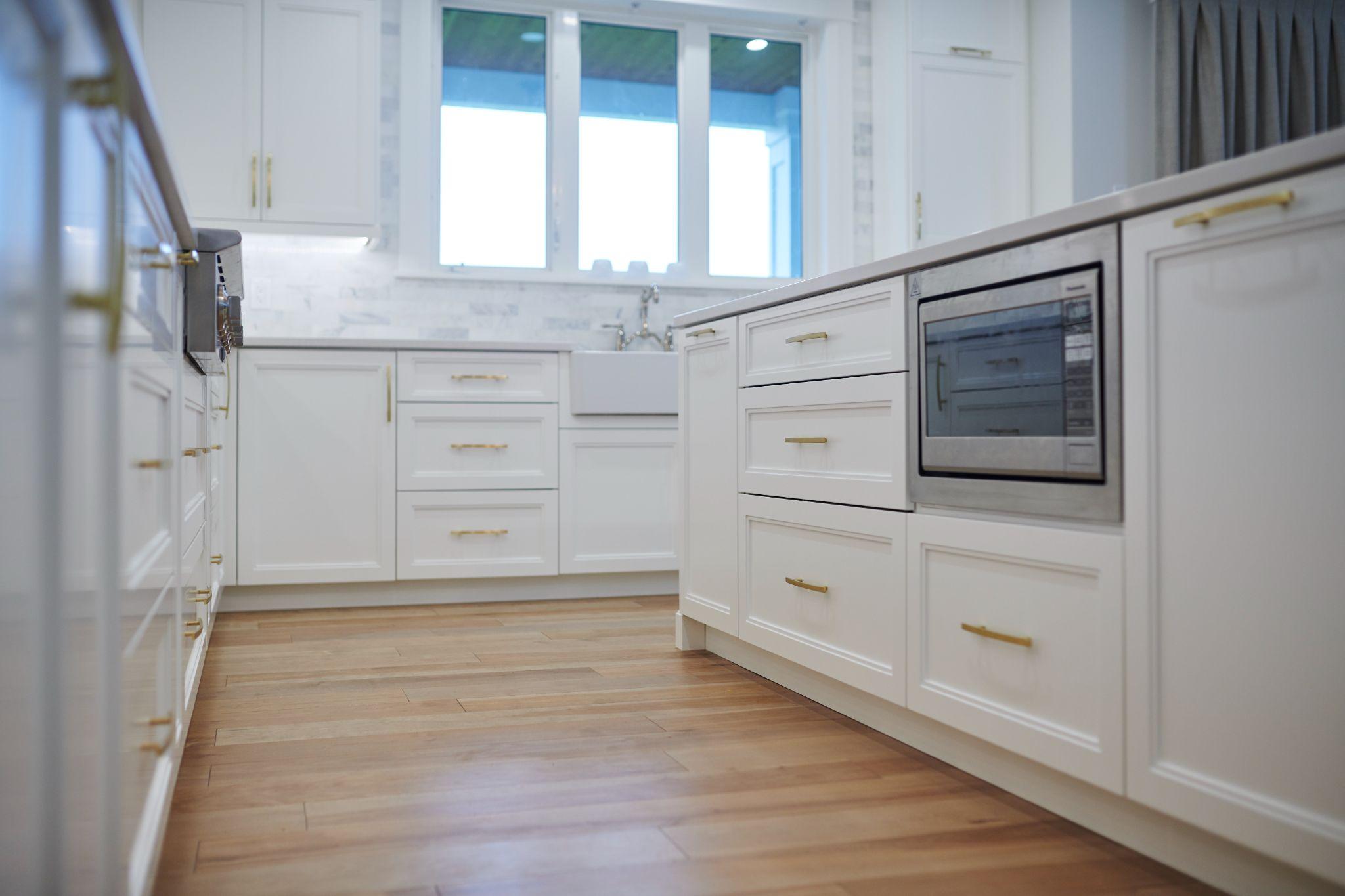 White kitchen cabinets with gold pulls and farmhouse sink