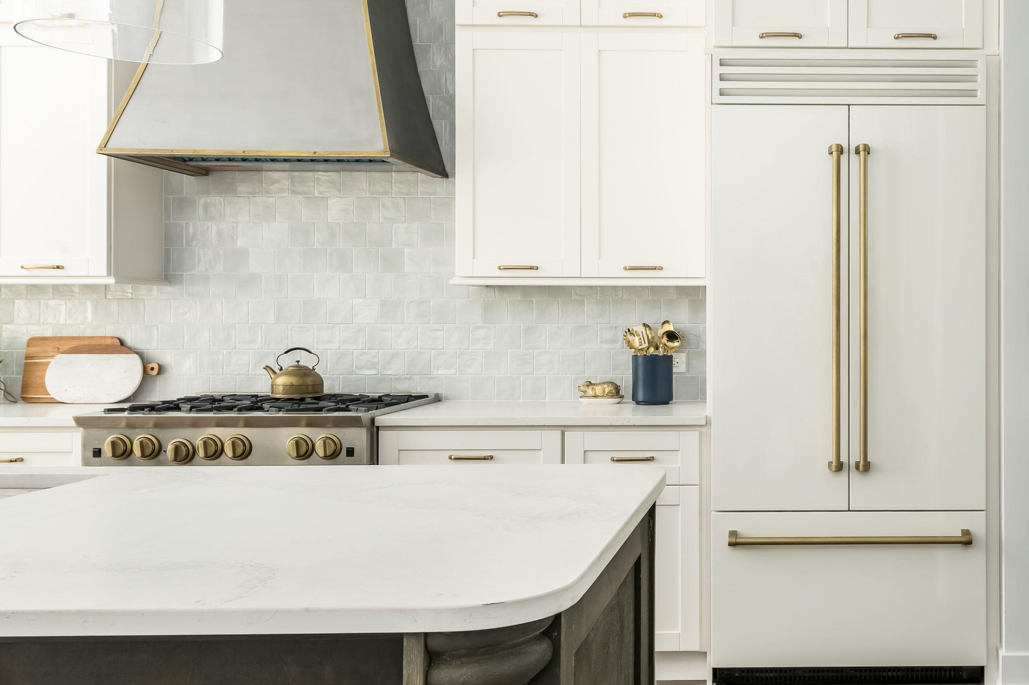 White shaker kitchen with gold hardware, zellige tile backsplash, and paneled refrigerator